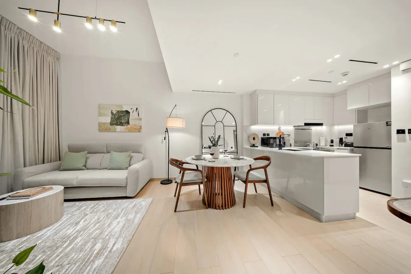 Sala y comedor de planta abierta con cocina y suelo de madera clara.