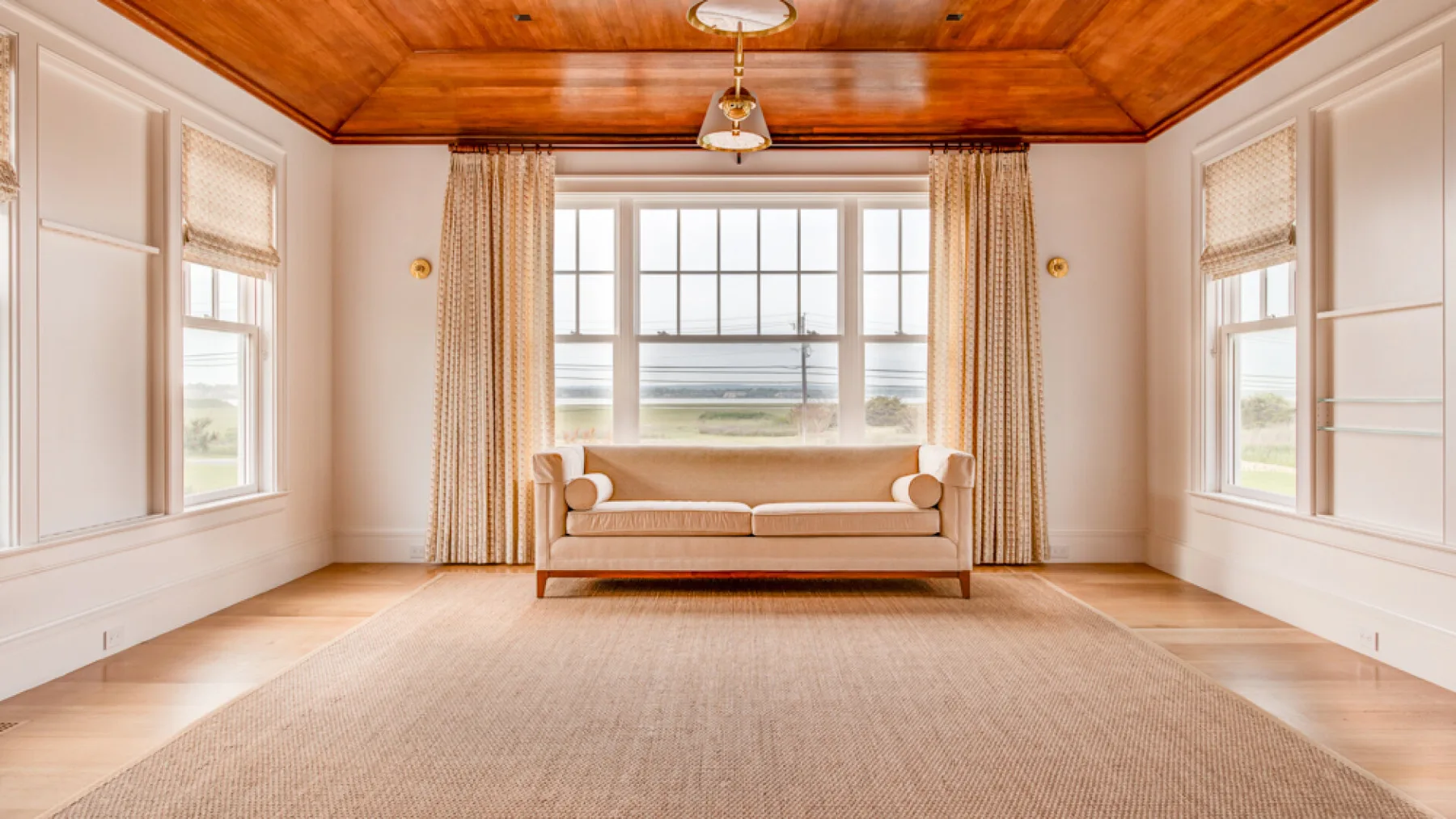 Una sala de estar luminosa con un sofá bajo una ventana grande.
