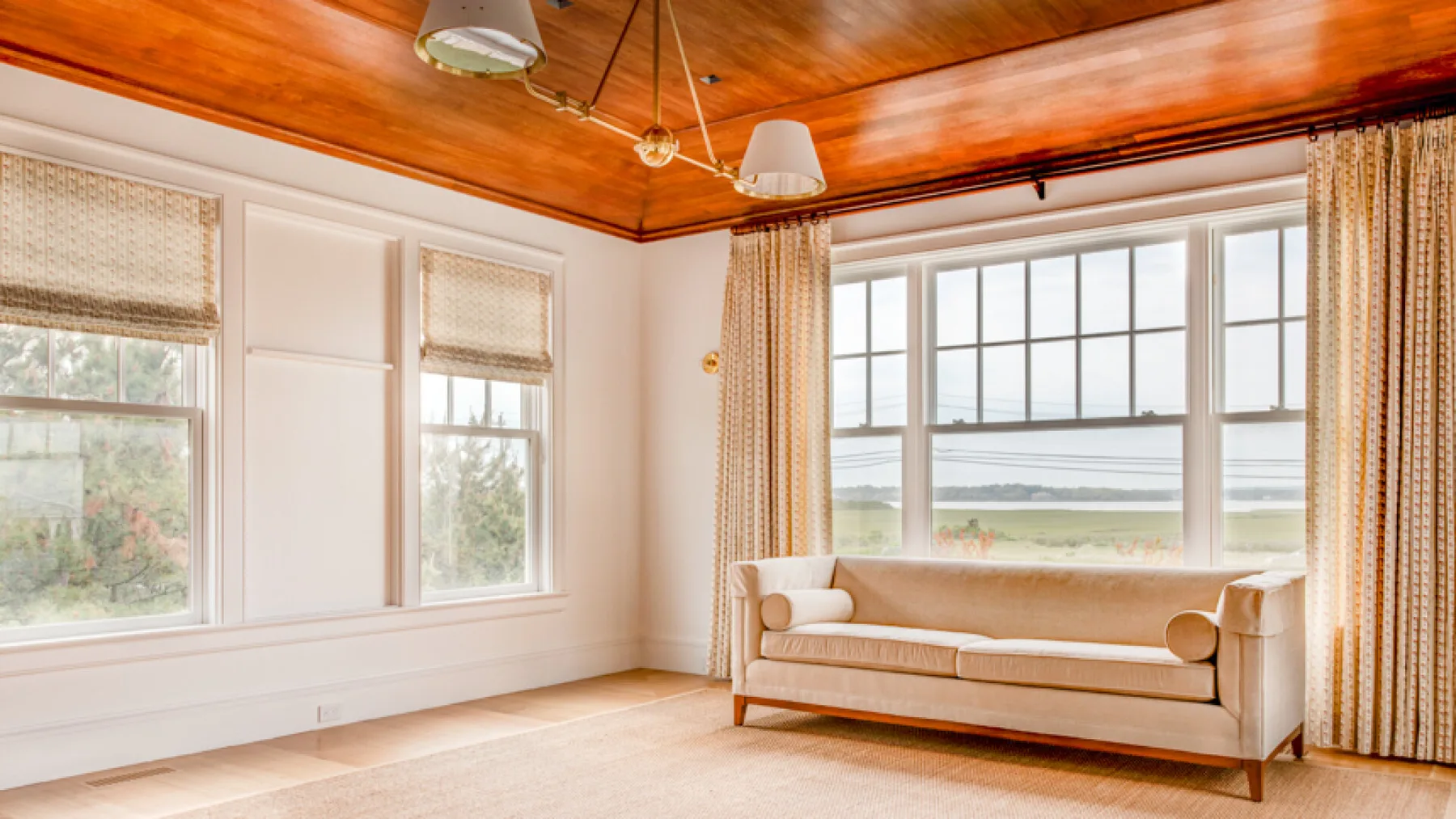 Una sala luminosa con un sofá junto a grandes ventanas con vistas al paisaje.