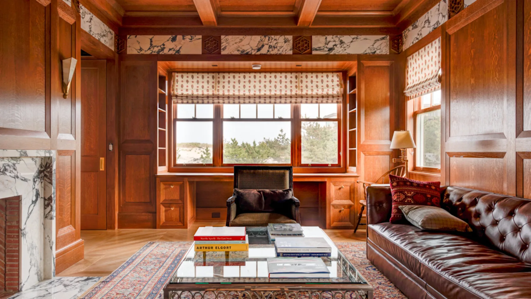 Una sala de estar revestida de madera con sofá, sillón y grandes ventanas.
