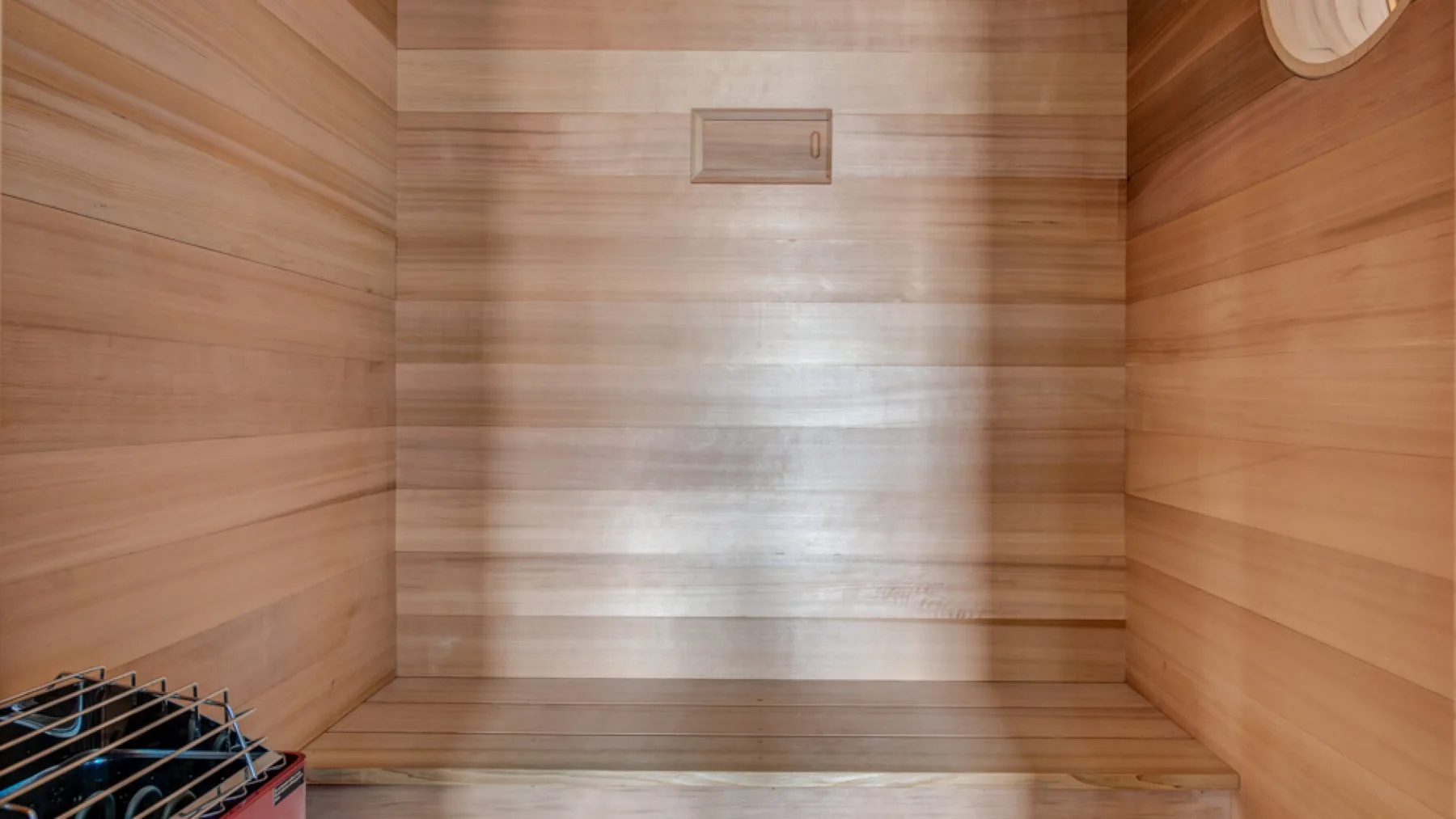 Una sauna de madera con asientos escalonados y un pequeño accesorio en la pared.