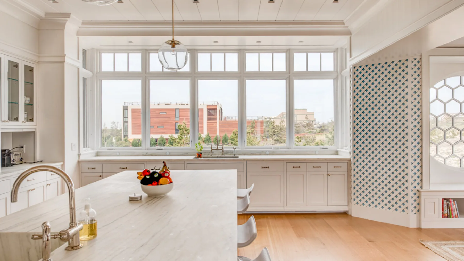Una cocina luminosa con una encimera larga, grandes ventanas y suelo de madera clara.