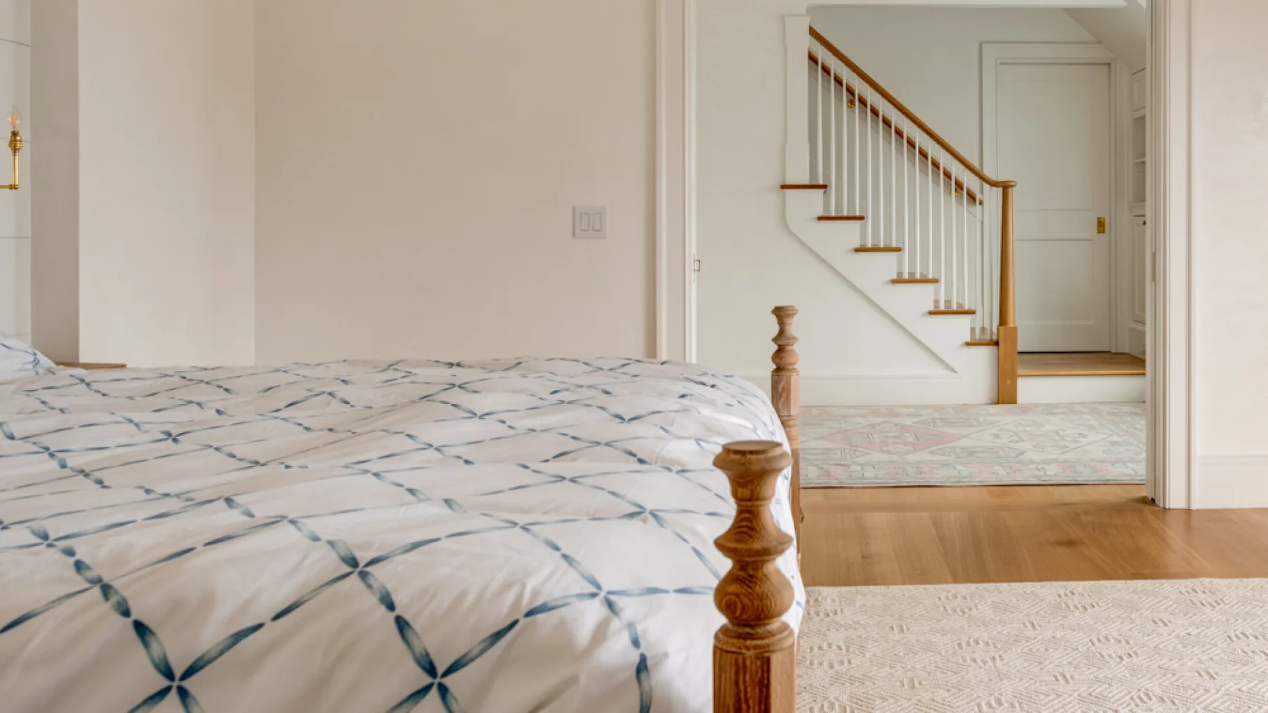 Un dormitorio con una colcha estampada junto a una escalera.