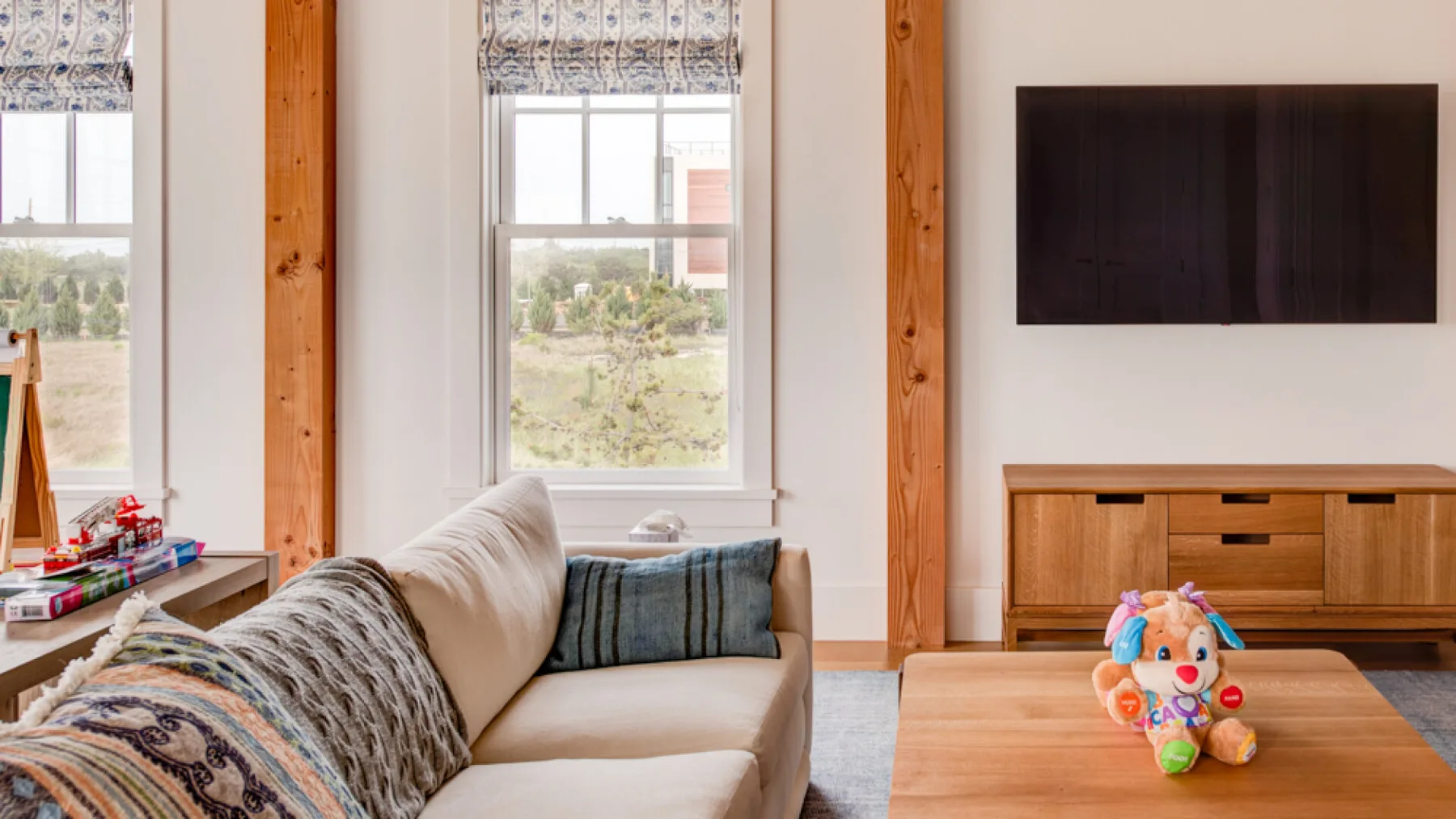 Una sala luminosa con un sofá, ventanas grandes y un televisor.