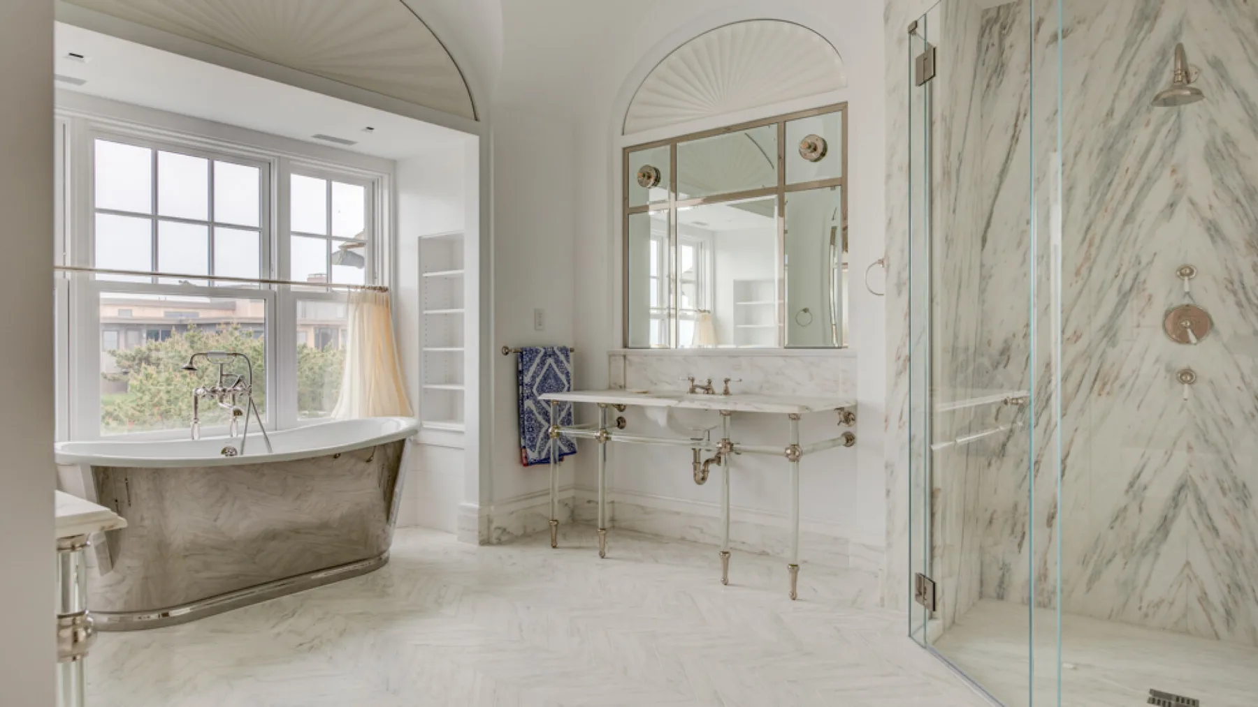 Un baño luminoso con bañera exenta, lavabo y ducha de cristal.
