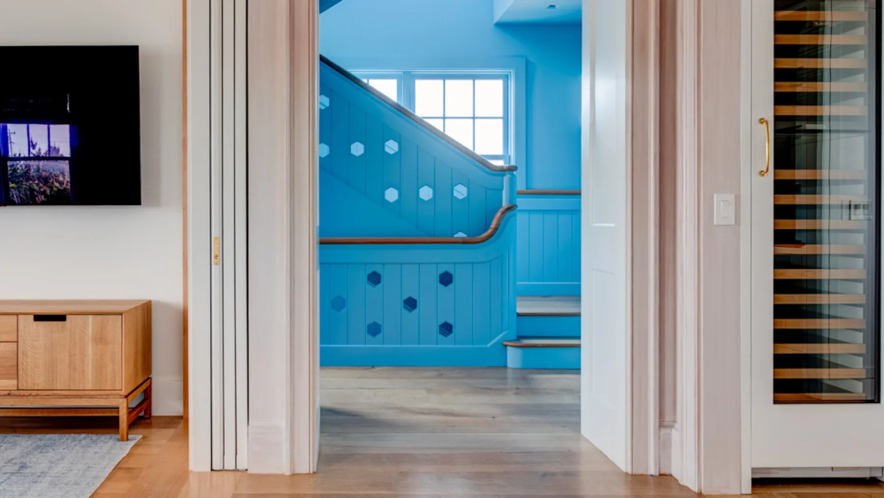 Un pasillo da a una escalera azul con una ventana encima.