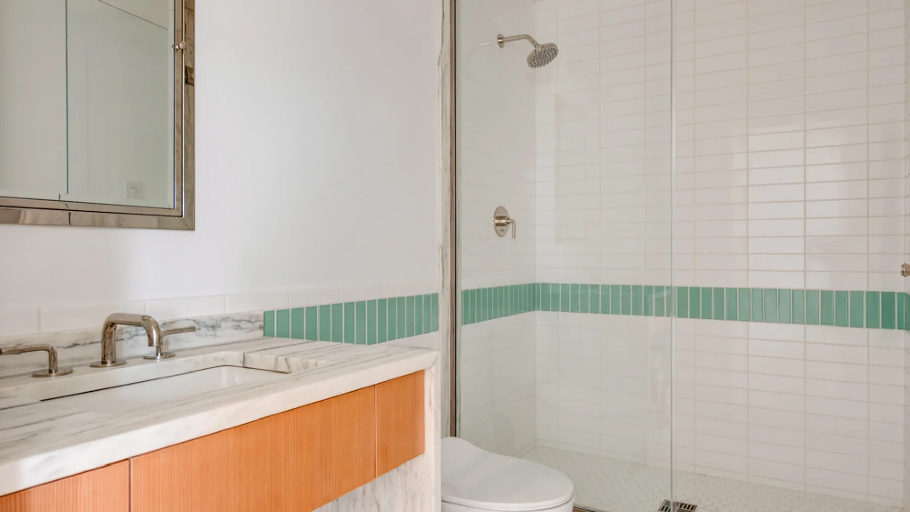 Un baño con un lavabo y tocador junto a una ducha alicatada.