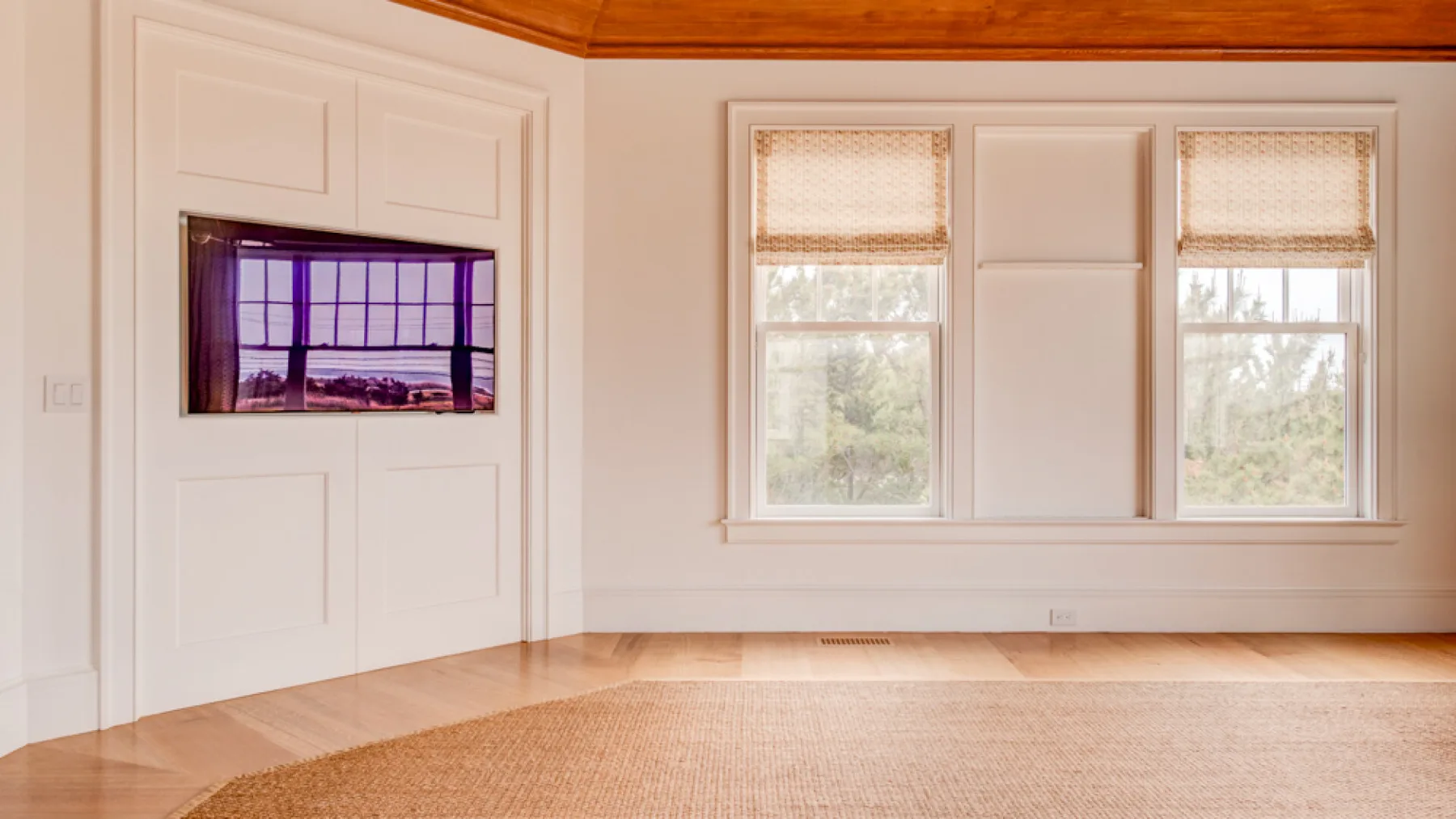 Una habitación luminosa con ventanales y una pantalla montada en la pared.