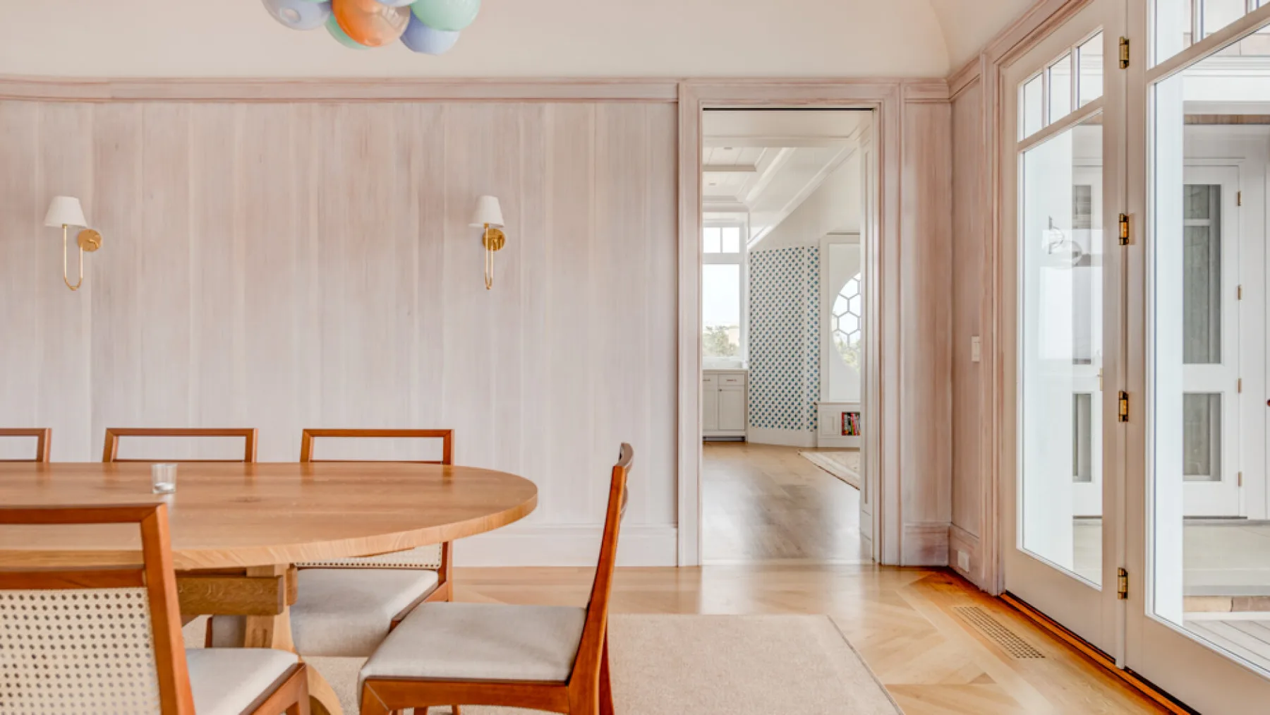 Comedor con una mesa de madera junto a puertas altas de vidrio.
