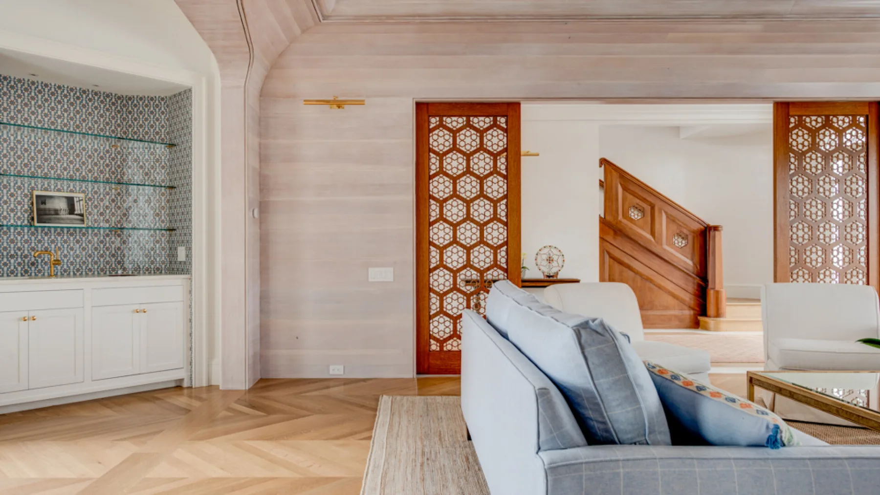 Una sala luminosa con asientos acolchados y una celosía decorada.