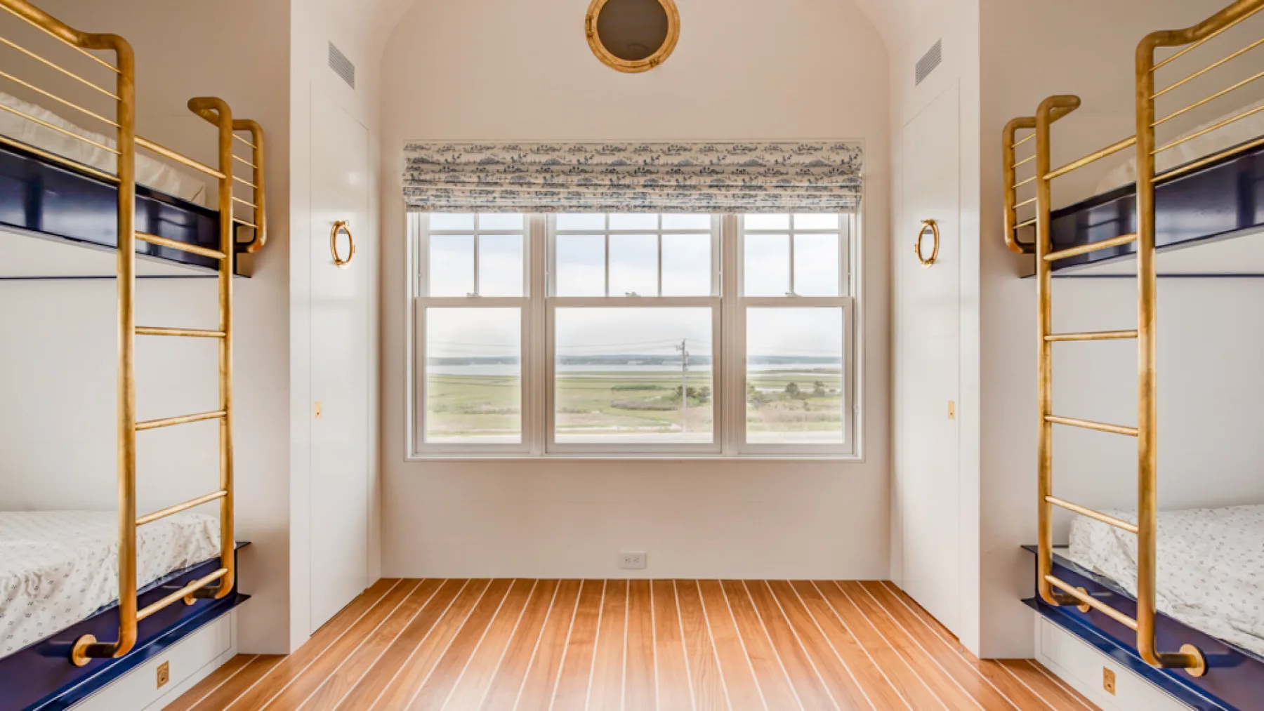 Un dormitorio luminoso con literas y una gran ventana con vista a campos abiertos.