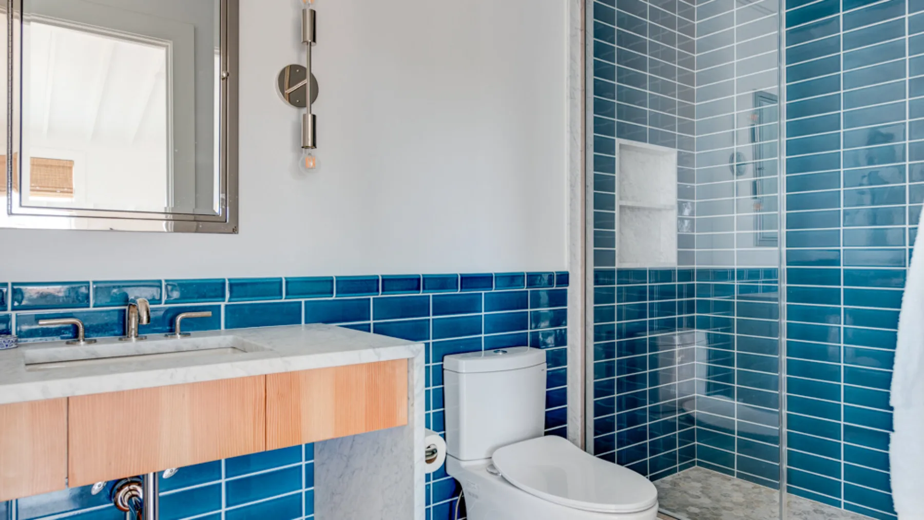 Un baño con lavabo, inodoro y ducha con azulejos azules.