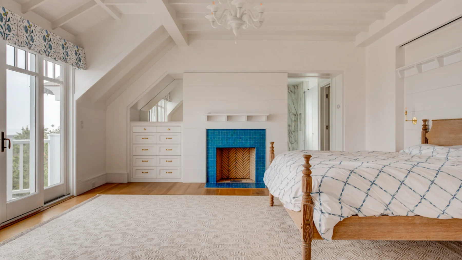 Un dormitorio luminoso con una chimenea y una cama grande junto a ventanales.