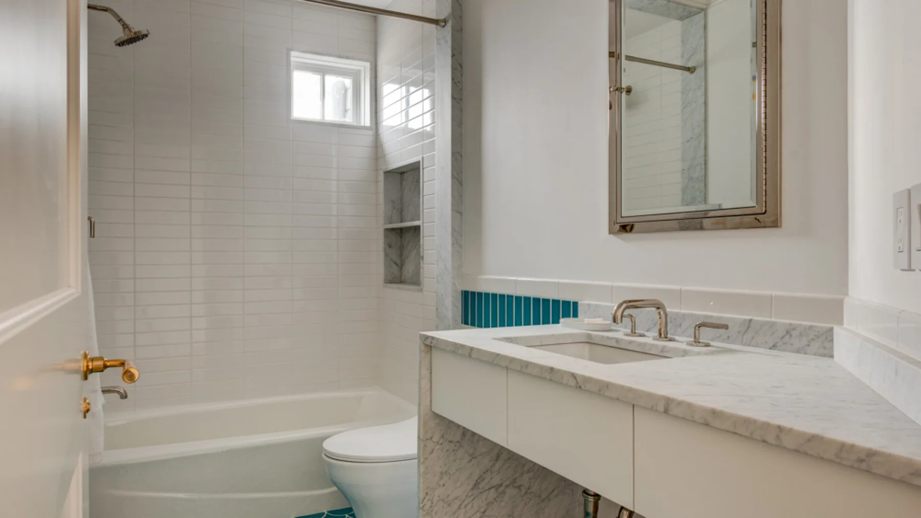 Un baño alicatado con bañera, inodoro y lavabo con mueble.