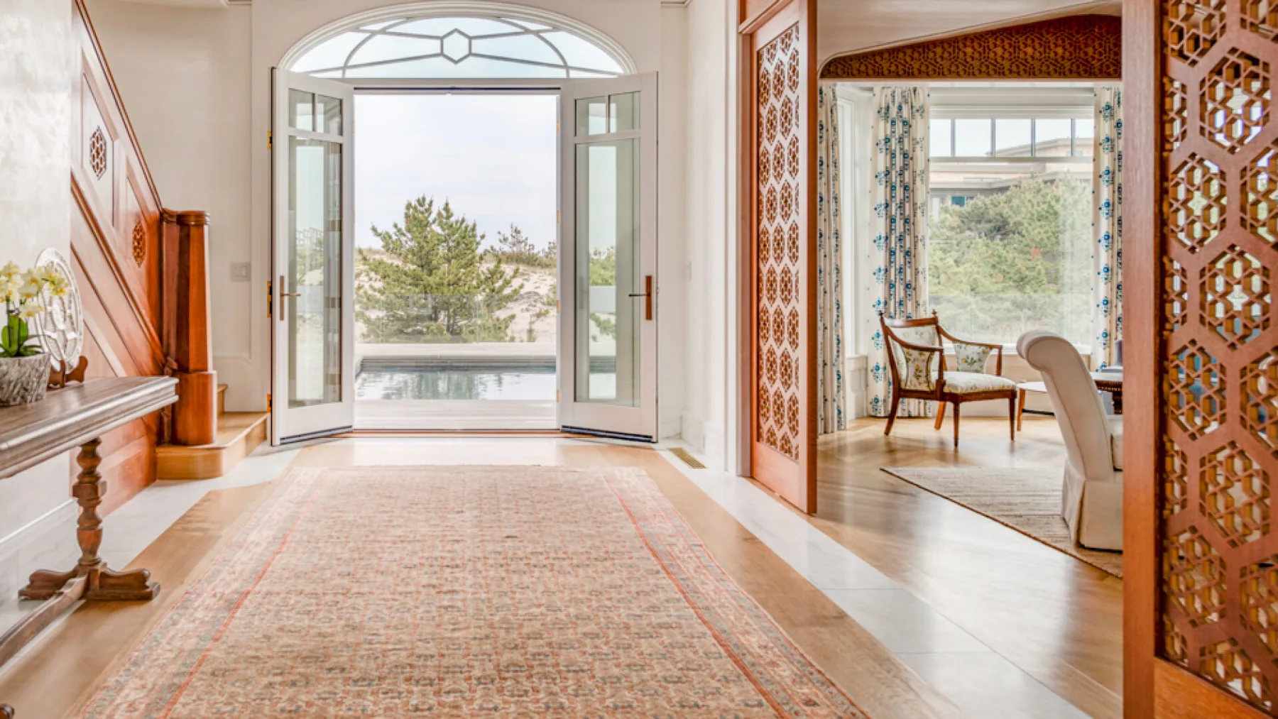 Un recibidor luminoso se abre hacia una gran ventana arqueada y una sala contigua.