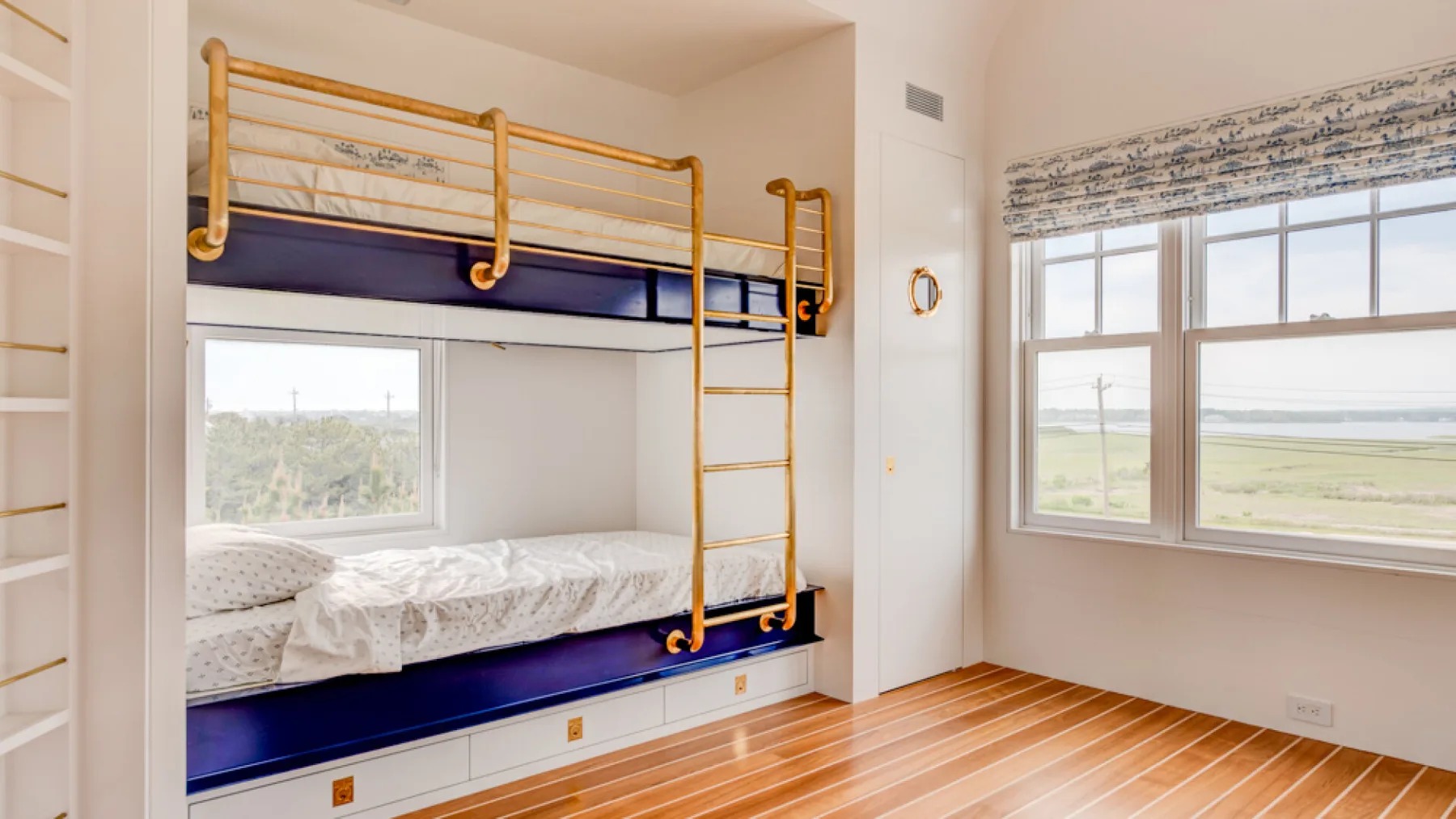 Un dormitorio luminoso con literas empotradas y ventanas grandes.