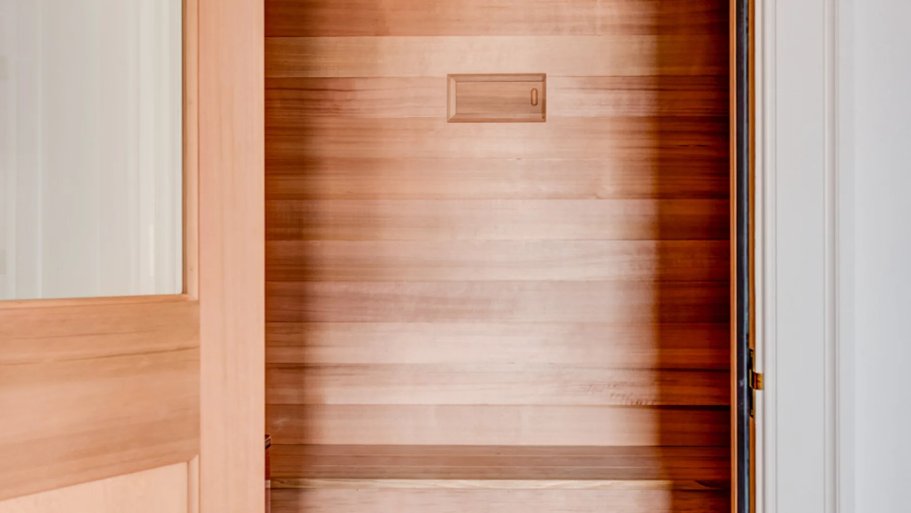 Una habitación revestida de madera con tablas horizontales y una pequeña placa en la pared.