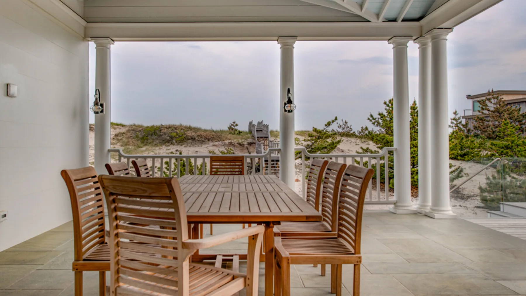 Una zona de comedor exterior cubierta, con mesa y asientos de madera, da al paisaje.
