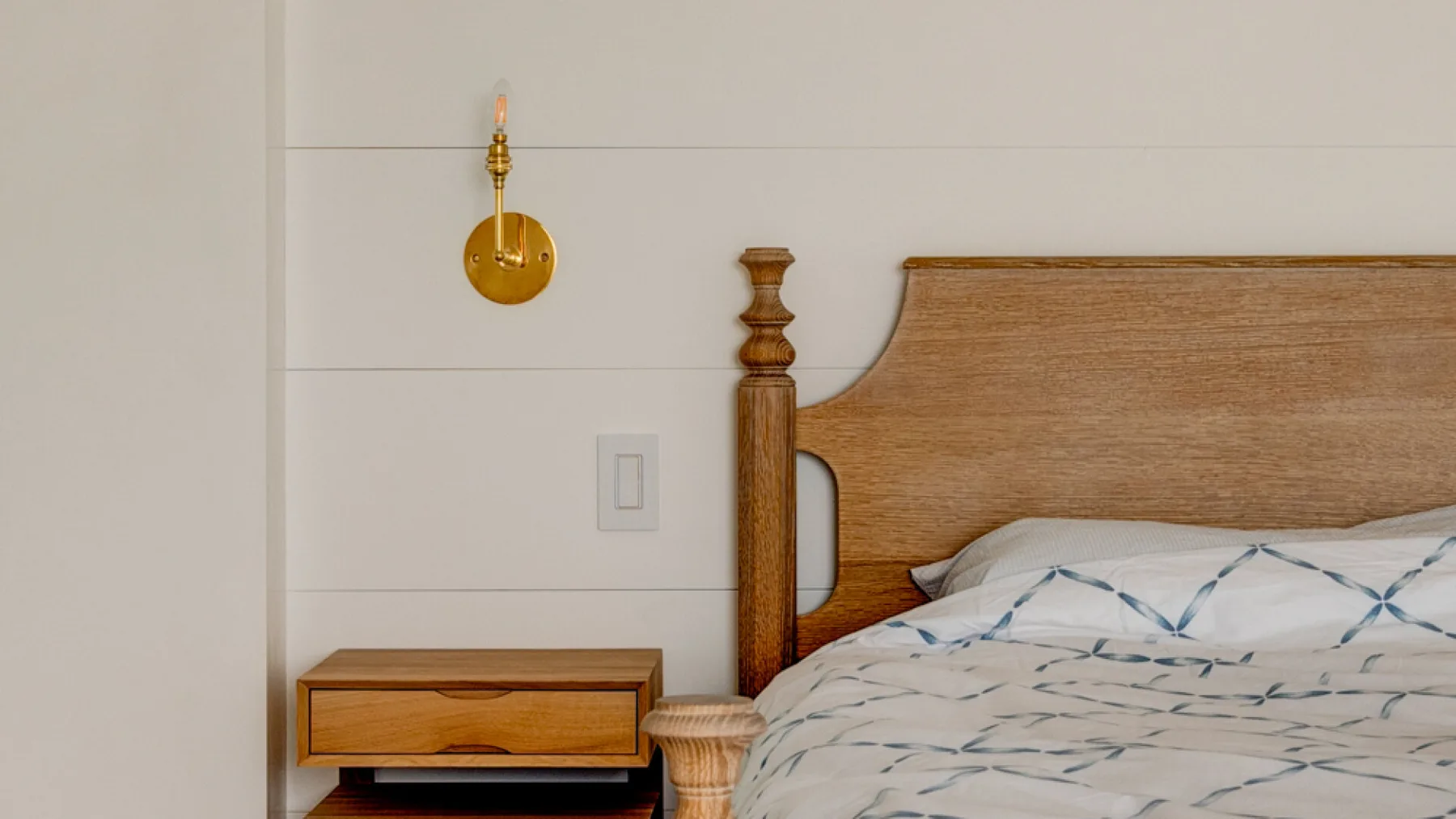 Un dormitorio con una cama de madera y ropa de cama estampada.