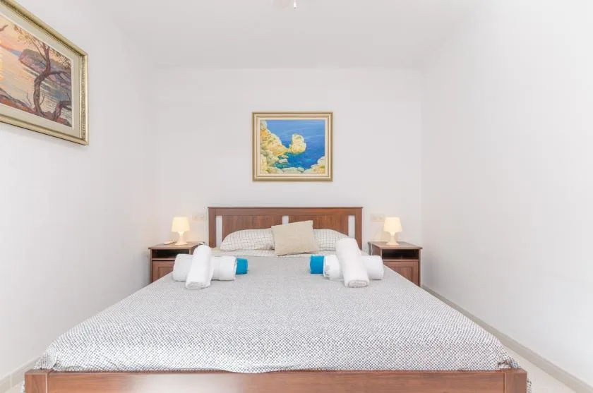 A bedroom with a neatly made bed and framed artwork above the headboard.