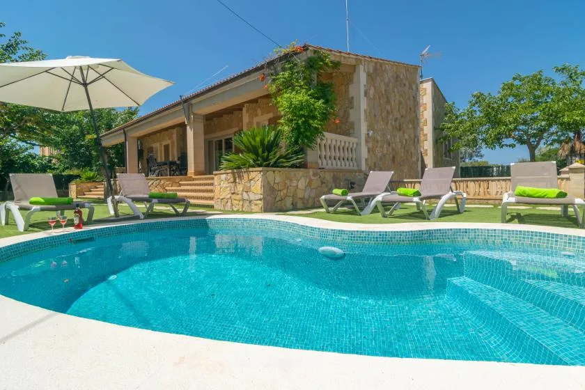 An outdoor swimming pool beside a low building and lounge seating.