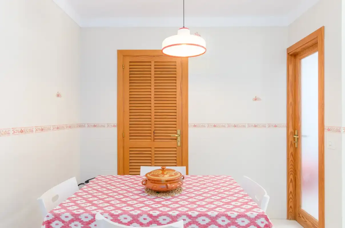 A dining area with a patterned tablecloth and wooden doors.