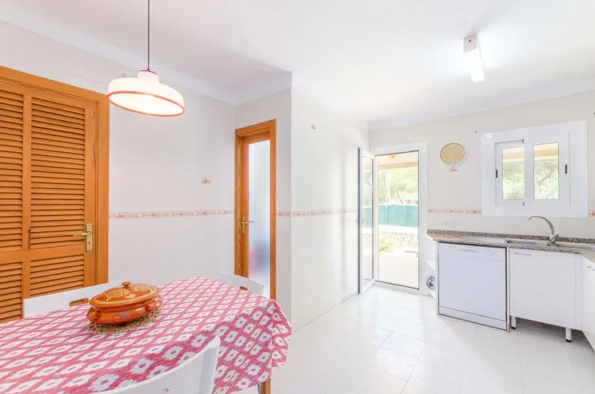 A bright kitchen and dining area with a patterned tablecloth and white cabinets.
