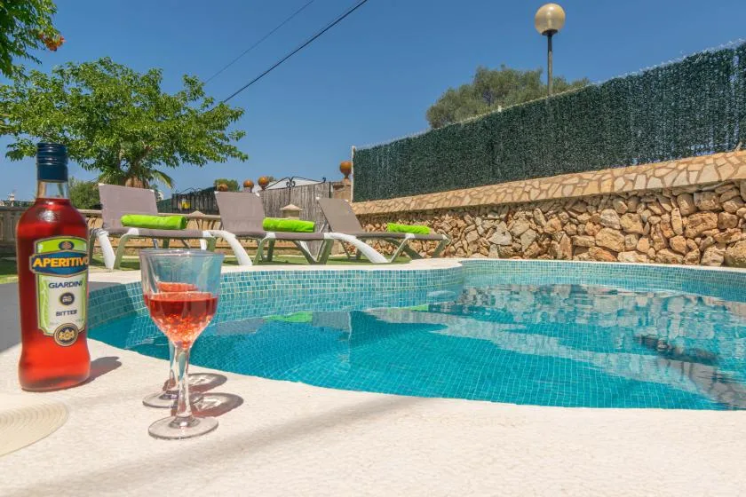 An outdoor swimming pool with lounge seating and a drink on the poolside.