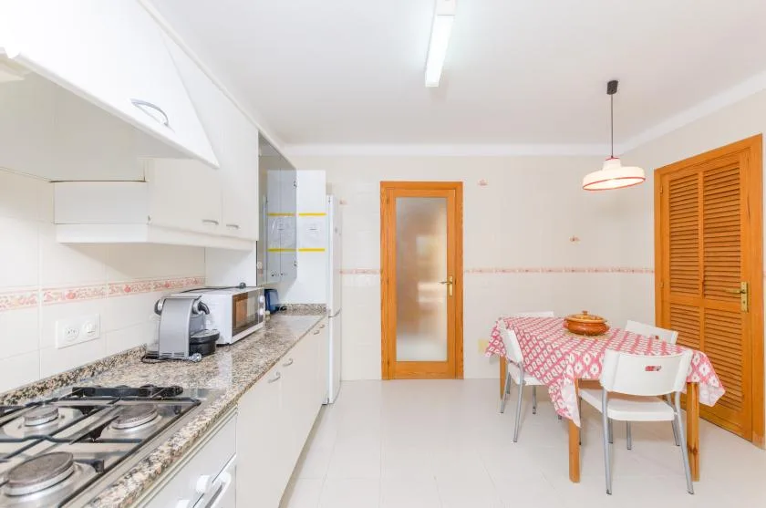 A bright kitchen and dining area with a counter, appliances, and a table.