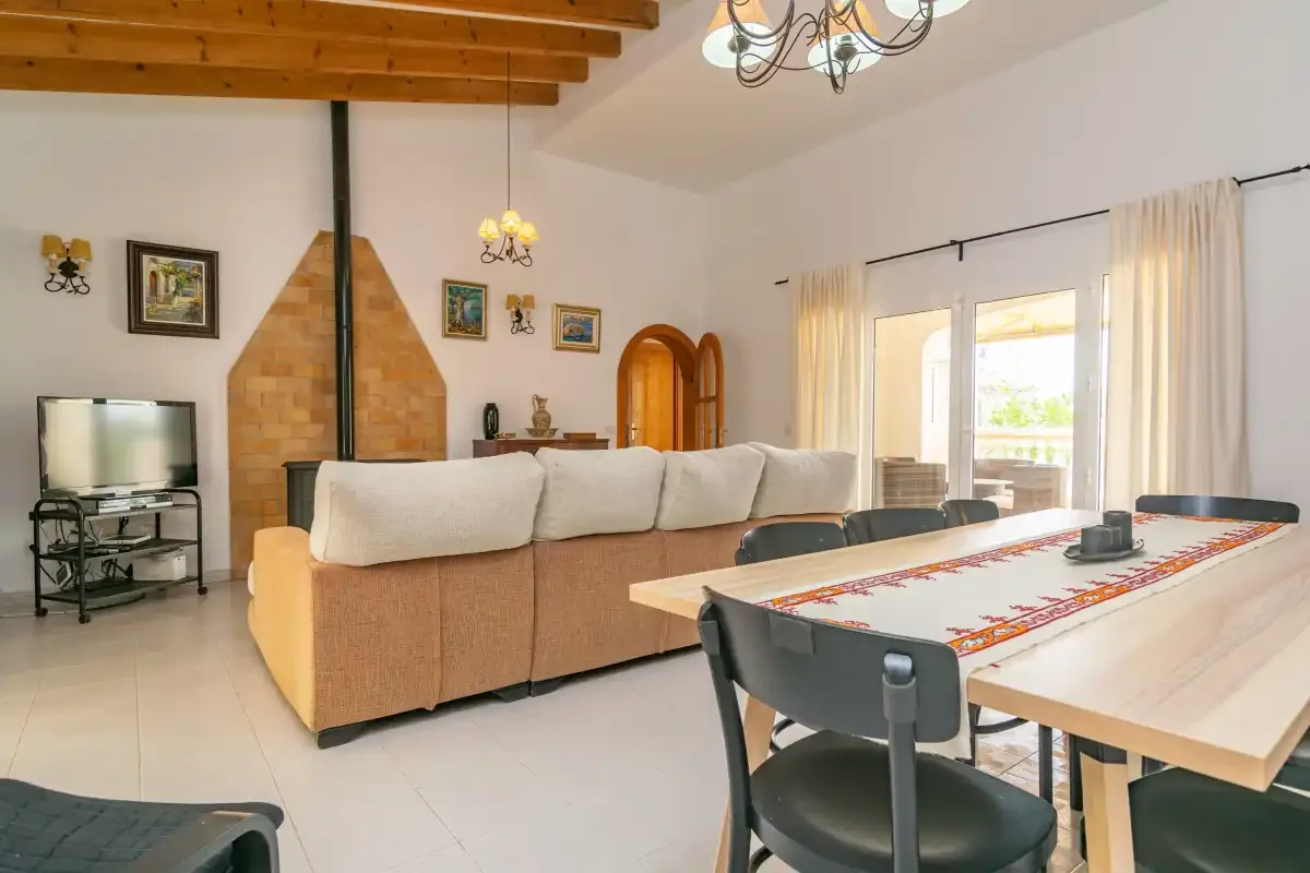 A living and dining area with a long table, seating, and a brick fireplace.