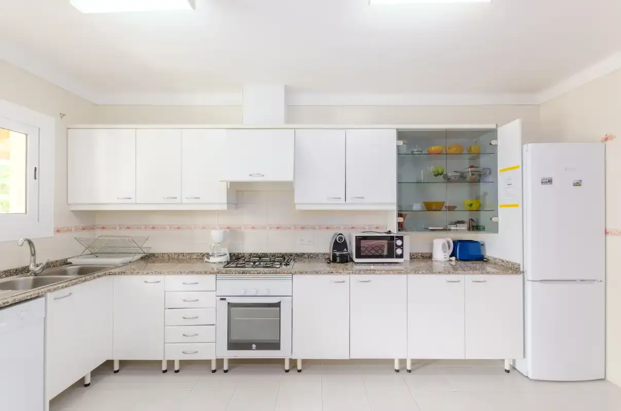 A bright kitchen with white cabinets, countertops, and appliances.