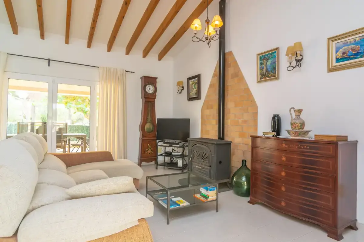 A bright living room with seating, a stove, and a wooden cabinet.