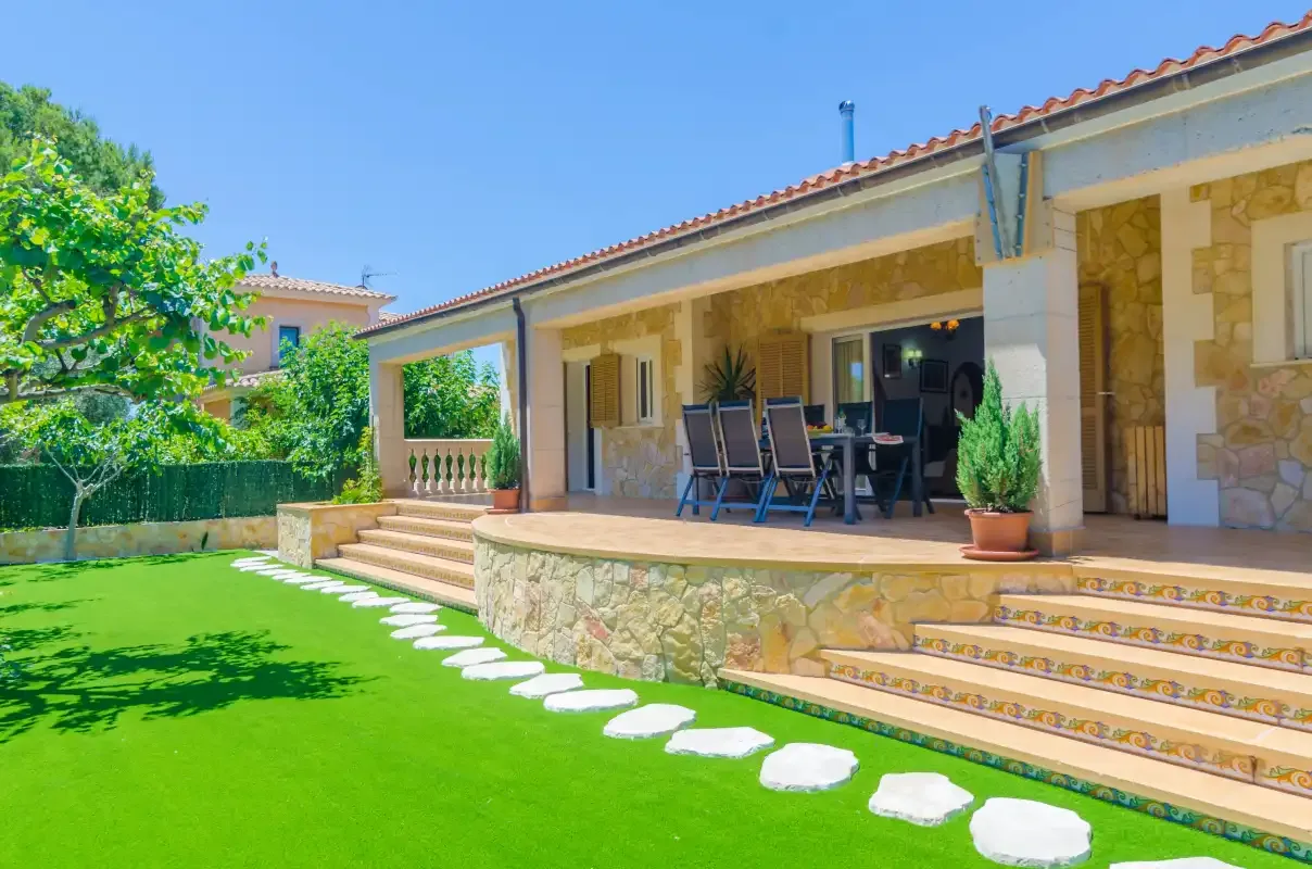 A covered patio with outdoor seating overlooks a green lawn.