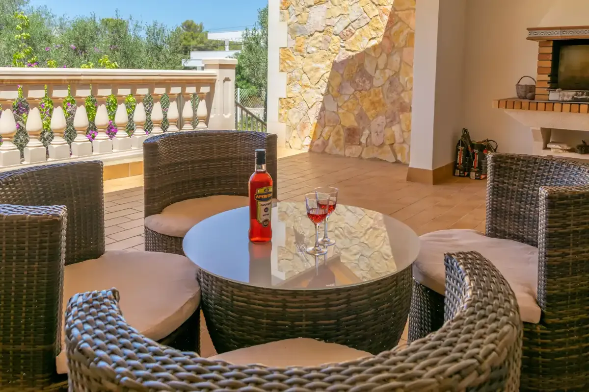 A furnished outdoor patio with woven seating and a round table.