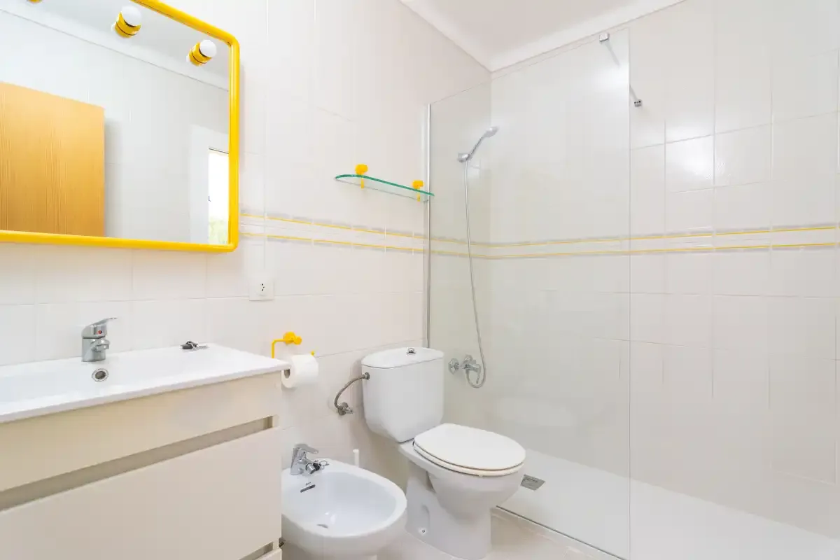 A bright tiled bathroom with a sink, toilet, and shower.