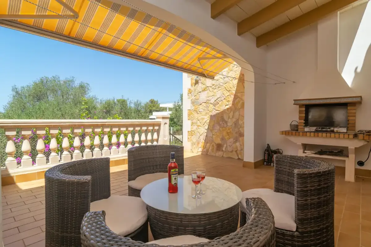 A covered outdoor seating area with a round table and a striped awning.