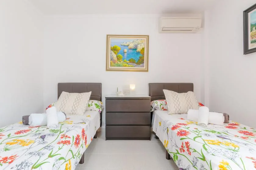 A twin bedroom with two beds featuring colorful floral bedding.