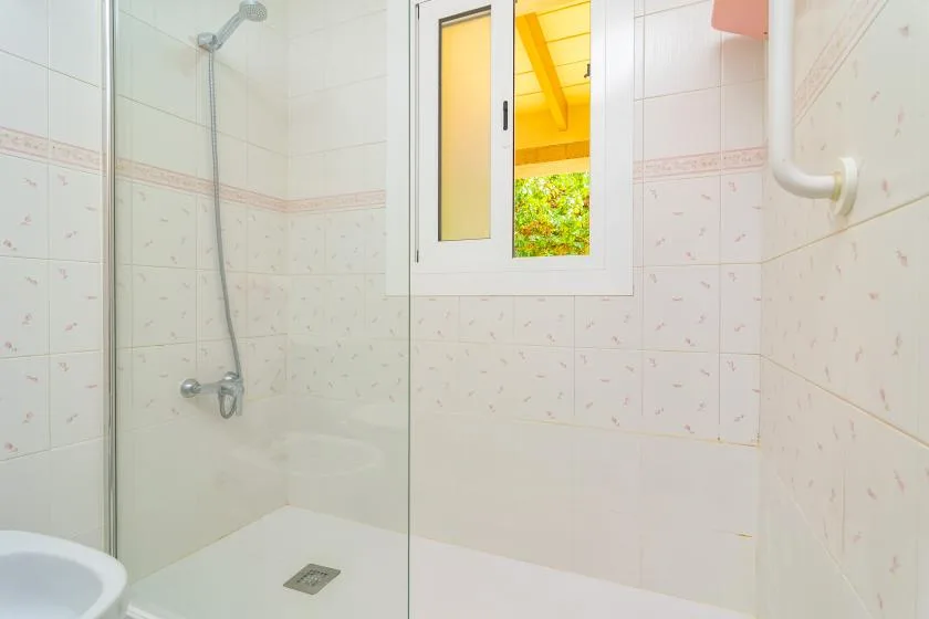 A tiled shower area with a small window above the shower floor.