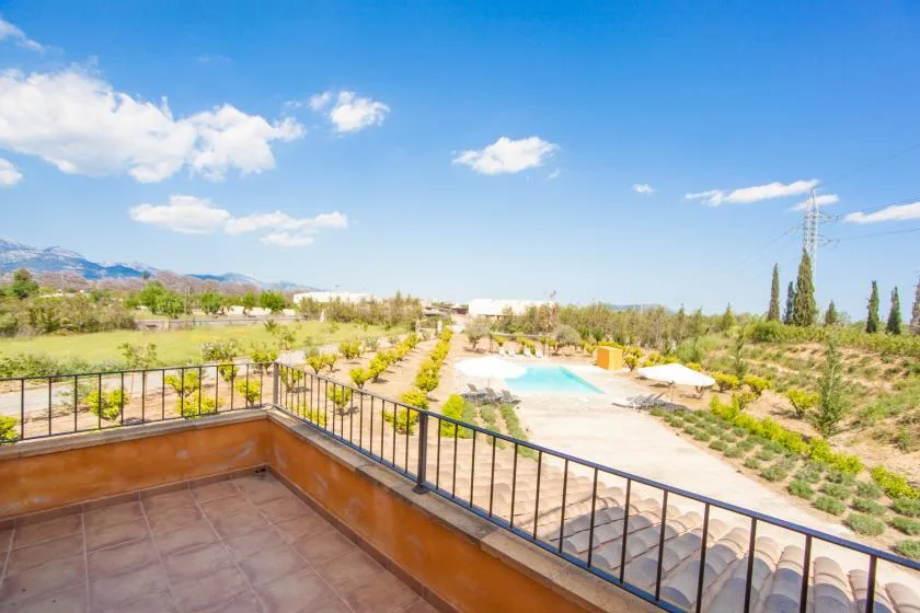 A tiled balcony overlooks a landscaped garden and outdoor swimming pool.