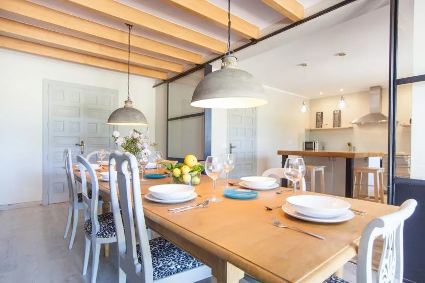 A dining area with a set table beneath exposed wooden ceiling beams.