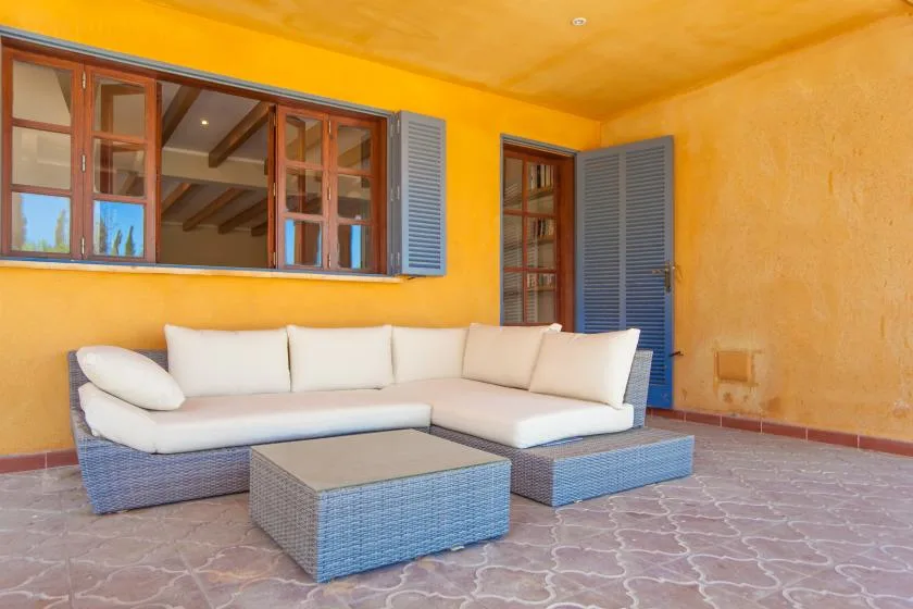 A covered patio with cushioned seating and a low table.