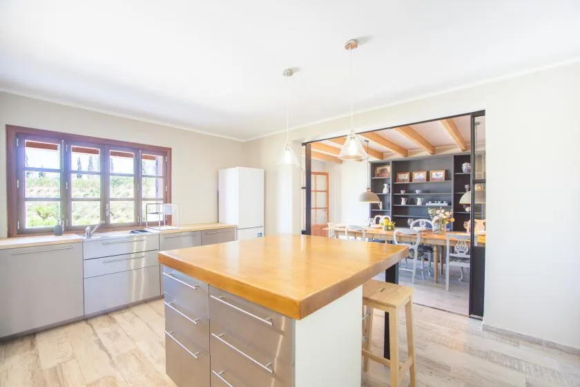 A bright kitchen with a large central island and a dining area beyond.