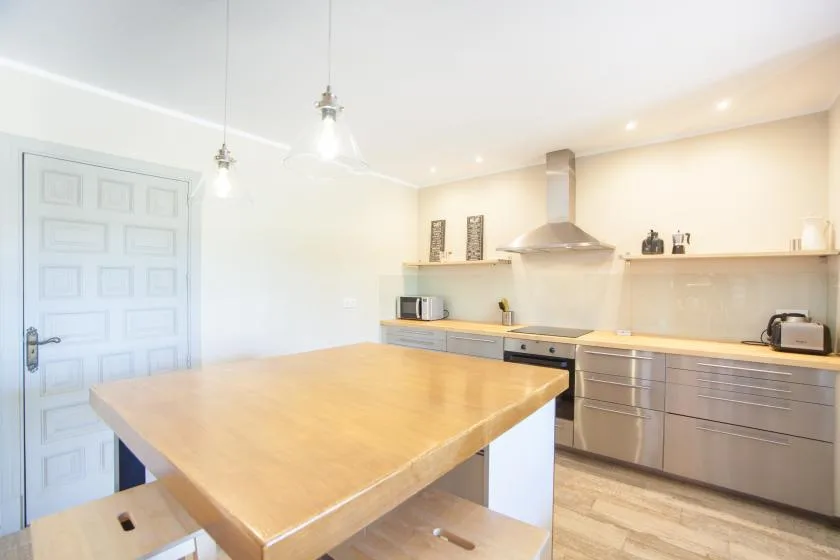 A bright kitchen with a large wooden island and stainless steel appliances.
