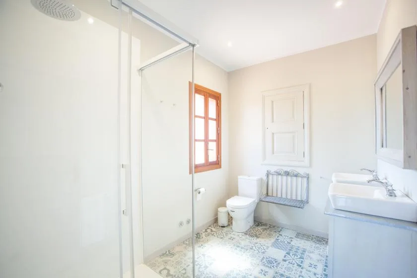 A bright bathroom with a glass shower, toilet, and sink.