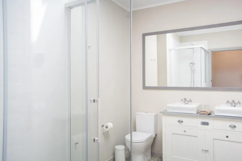 A bright bathroom with a glass shower, toilet, and sink vanity.