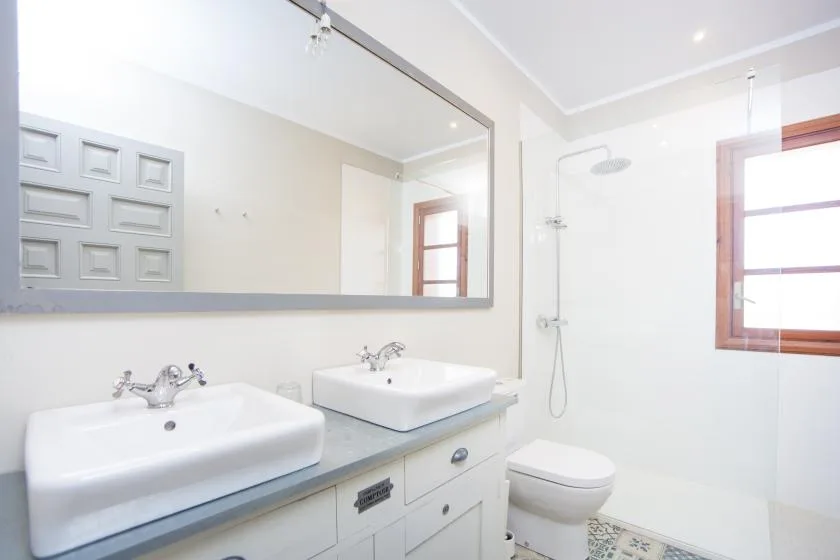 A bright bathroom with a double sink vanity and a shower.