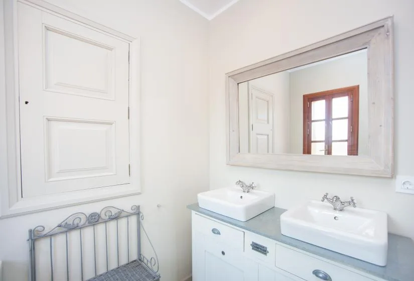 A bright bathroom with two sinks and a large wall mirror.