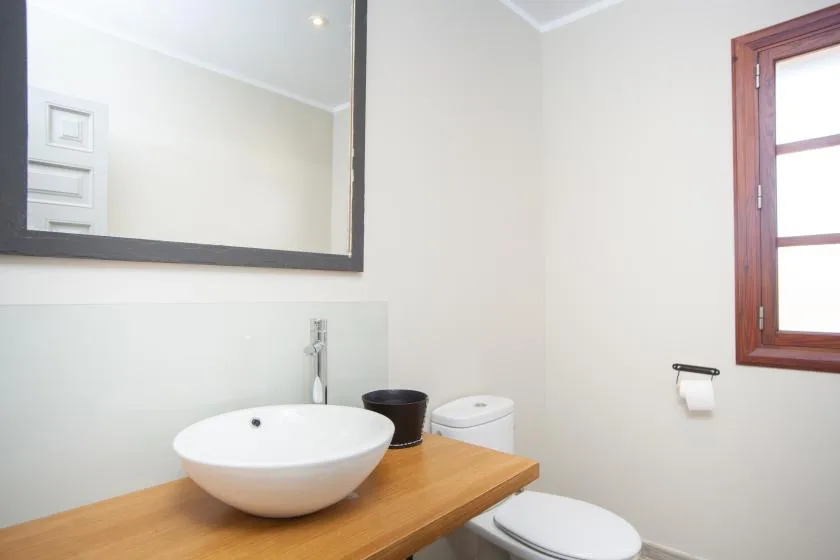 A bathroom vanity with a vessel sink, mirror, and toilet.