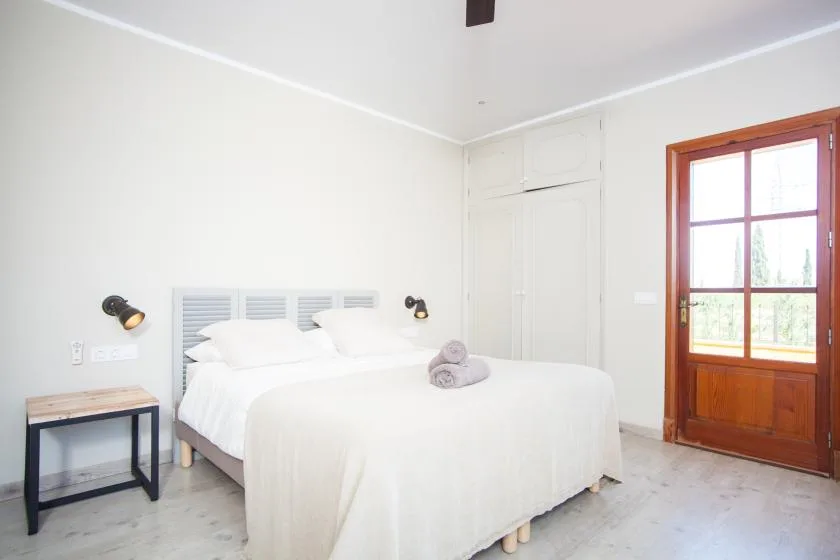 A bright bedroom with a double bed and a wood-framed glass door.
