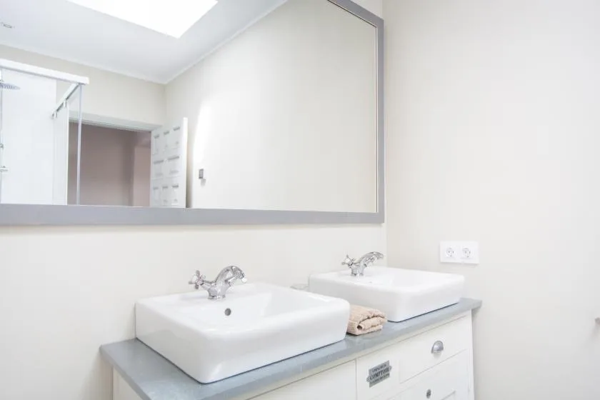 A bright bathroom with two sinks beneath a large mirror.